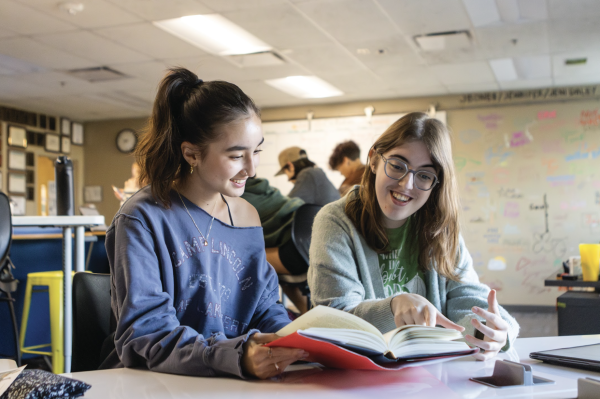 Talking about a book, seniors Anwen Williams and Gillian Sellet smile during a meeting. Williams, the vice president, and Sellet, the president, both organize and uphold meetings for the National English Honor Society chapter.